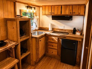 A compact kitchen with wooden cabinetry, a stainless steel sink, and a black refrigerator.