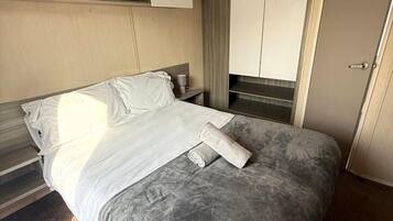 Et hotelværelse med seng, natbord, garderobeskab og en dør.