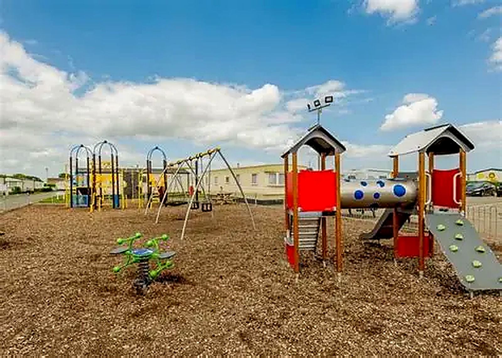 A playground with various play structures including swings, slides, and climbing areas.