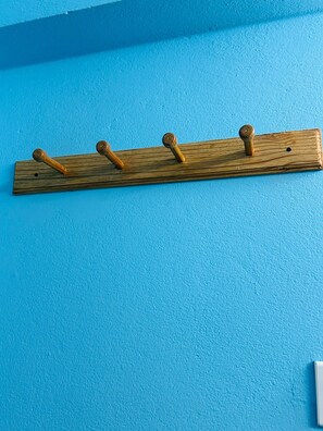 Ein hölzerner Kleiderhaken mit vier Haken an einer blauen Wand.
