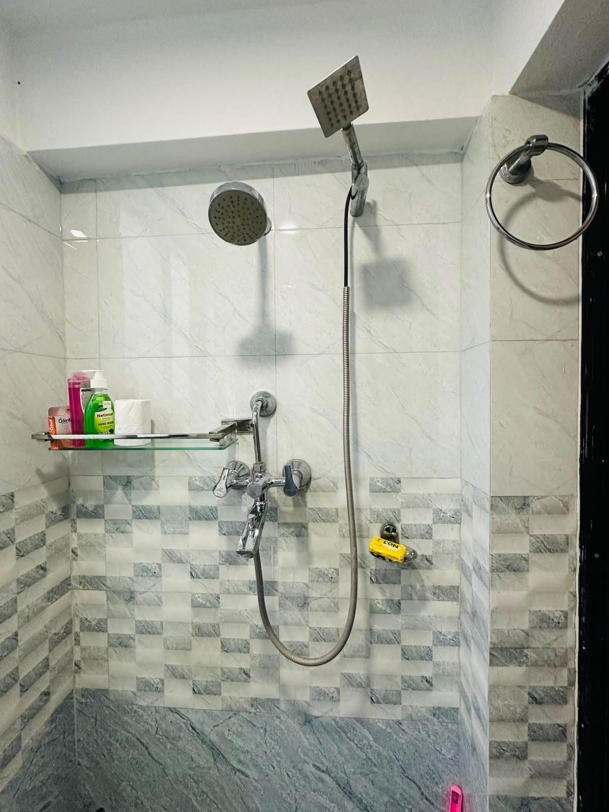 A shower area with a handheld showerhead, a fixed showerhead, and a handheld shower hose.
