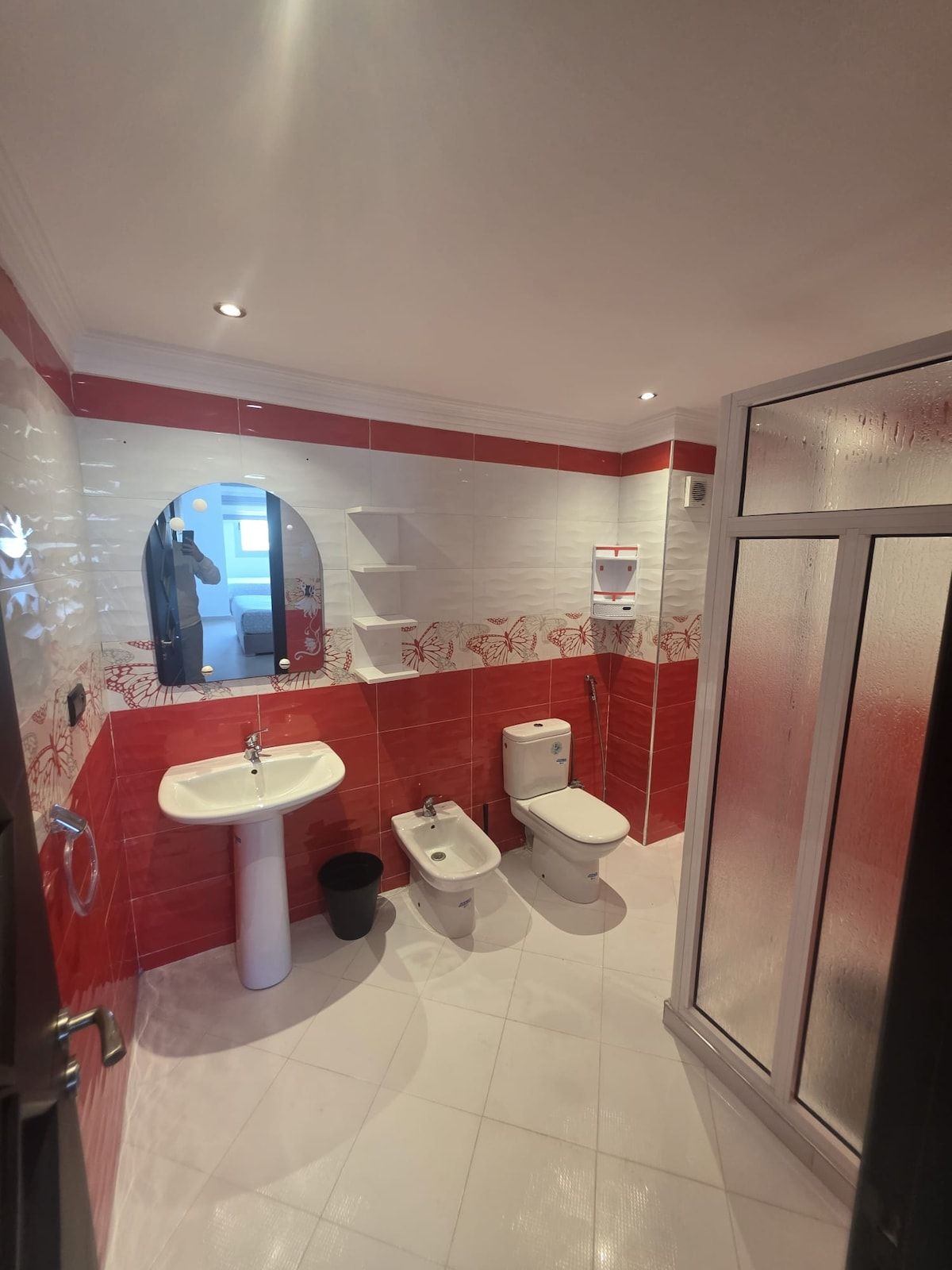 A bathroom with a white sink, a bidet, a toilet, and a shower area.