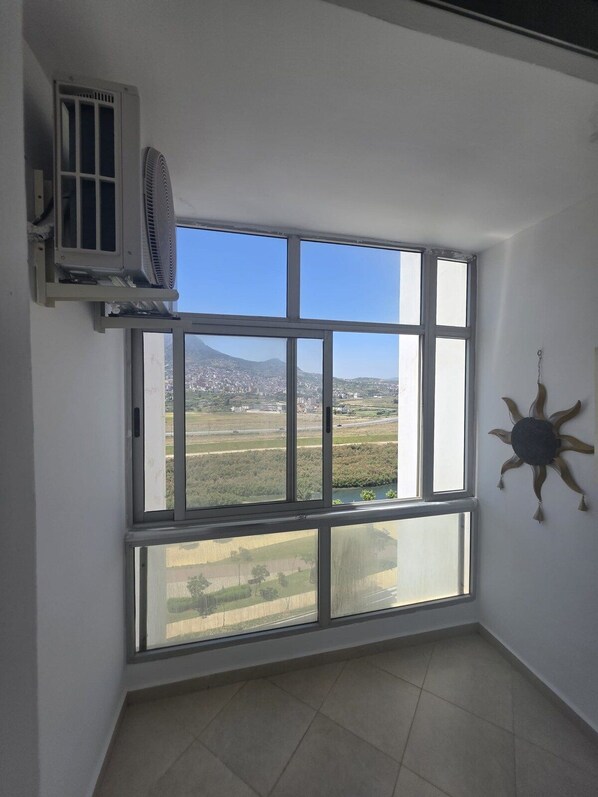 Una habitación con un ventanal grande, un equipo de aire acondicionado y un adorno en la pared.
