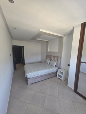 Un dormitorio moderno con una cama grande, una mesita de noche y un cabecero empotrado.