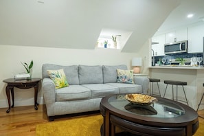 A living room with a grey sofa, a glass coffee table, and a small side table with a plant.