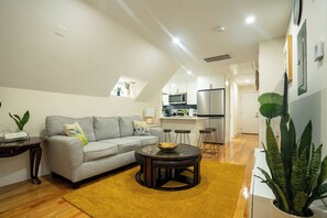 A modern living room with a sofa, a coffee table, and a kitchen in the background.