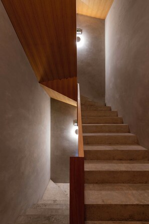 Eine Treppe mit Holzgeländer und Betonboden, die nach oben führt.