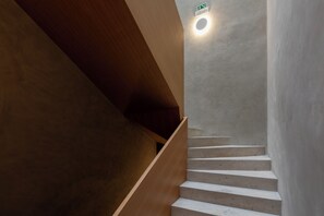 Un escalier avec une rampe en bois et un luminaire fixé au mur.