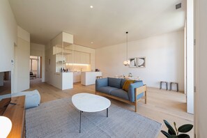 Ein modernes Wohnzimmer mit einer Couch, einem Couchtisch und einer Küche im Hintergrund.
