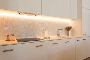A modern kitchen with white cabinets, a marble countertop, a built-in oven, and a small sink. - Tripas-Coração: Mouzinho32 1st Floor Apt D (Porto)