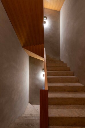 Una escala amb barana de fusta i un lluminari al capdamunt.
