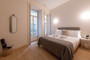 Une chambre à coucher avec un lit, une table de chevet, une lampe et une vue sur l’extérieur.