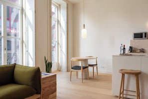Une cuisine moderne avec une table à manger en bois, des tabourets de bar et un luminaire suspendu.