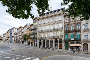 A street with historic buildings, a pedestrian, and a storefront. - Tripas-Coração: Mouzinho32 Rooftop E (Porto)