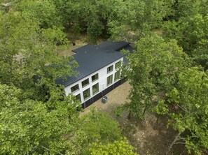 A modern house surrounded by dense greenery. - Romantic Forest Escape | Hot Tub + Soaking Tub (Broken Bow)