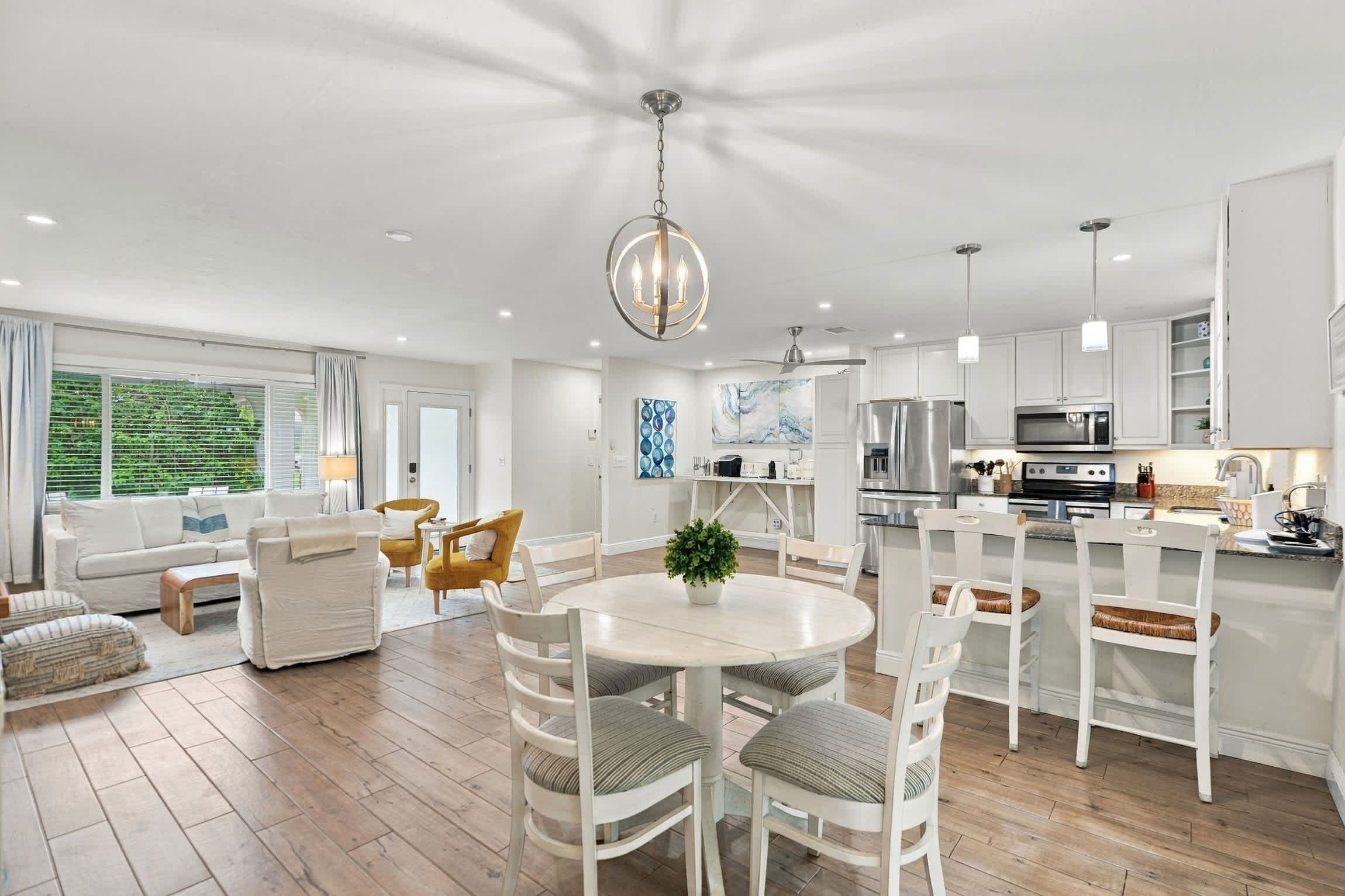 A modern kitchen with white cabinetry, stainless steel appliances, and a dining area with a round table and chairs.