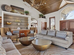 Ein geräumiges Wohnzimmer mit einem großen Ecksofa, zwei runden Couchtischen und einer Holzbalkendecke.