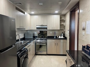 A modern kitchen with stainless steel appliances, wooden cabinets, and a black countertop. - VESTA  - Superior Suite - 2BR - Partial Nile View (Cairo)