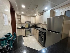 Eine moderne Küche mit Edelstahlgeräten, Holzschränken und einer schwarzen Arbeitsplatte.