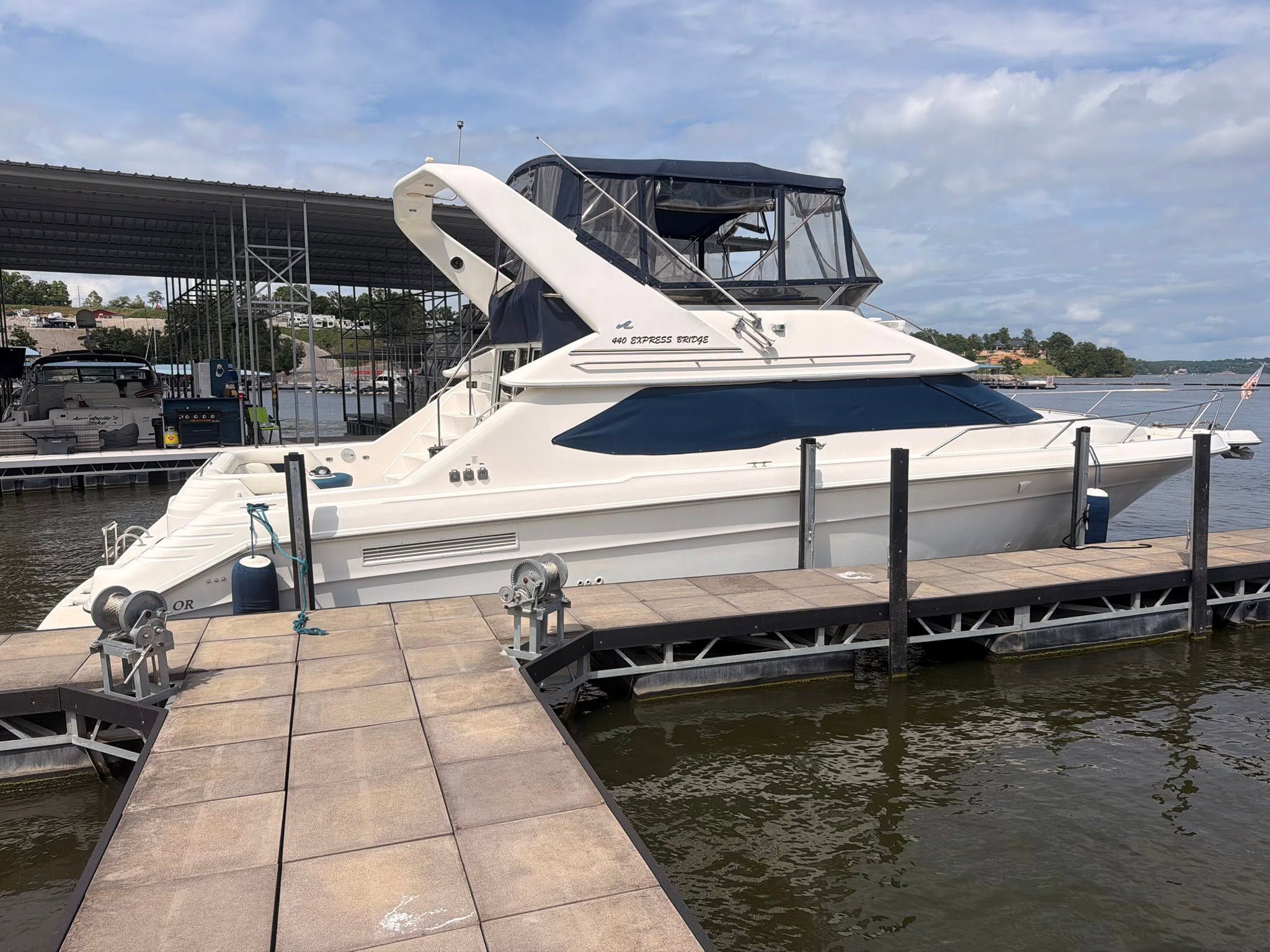 A yacht docked at a marina with a covered area and a wooden dock.