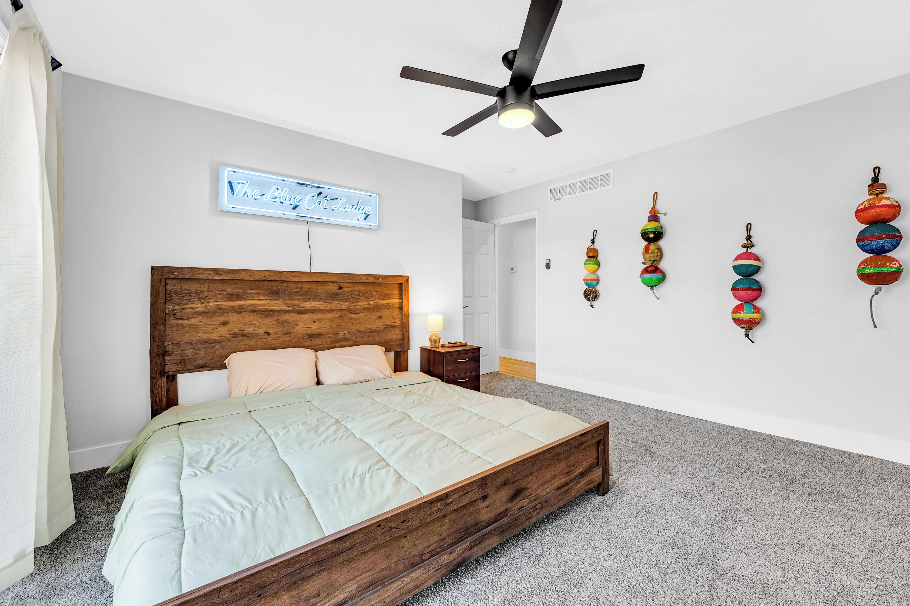 Ein Schlafzimmer mit einem hölzernen Bett, einem Deckenventilator, einem an der Wand befestigten Schild und bunten Wanddekorationen.