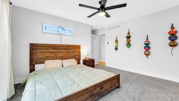Ein Schlafzimmer mit einem hölzernen Bett, einem Deckenventilator, einem an der Wand befestigten Schild und bunten Wanddekorationen.