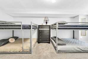 Quarto com beliche, cômoda e luminária.