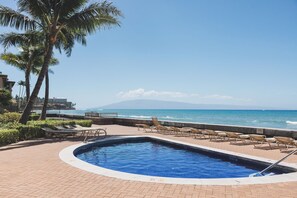 A swimming pool with lounge chairs and a view of the ocean. - New unit to rent.  Adorable 1 bed/1 bath condo. (Lahaina)