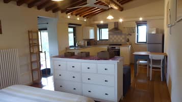 Een slaapkamer met een bed, een dressoir en een kitchenette met een fornuis en een spoelbak.