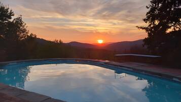 Una piscina con vista despejada al atardecer y montañas al fondo.