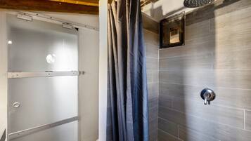 Un baño con ducha, puerta de vidrio y pared con azulejos.