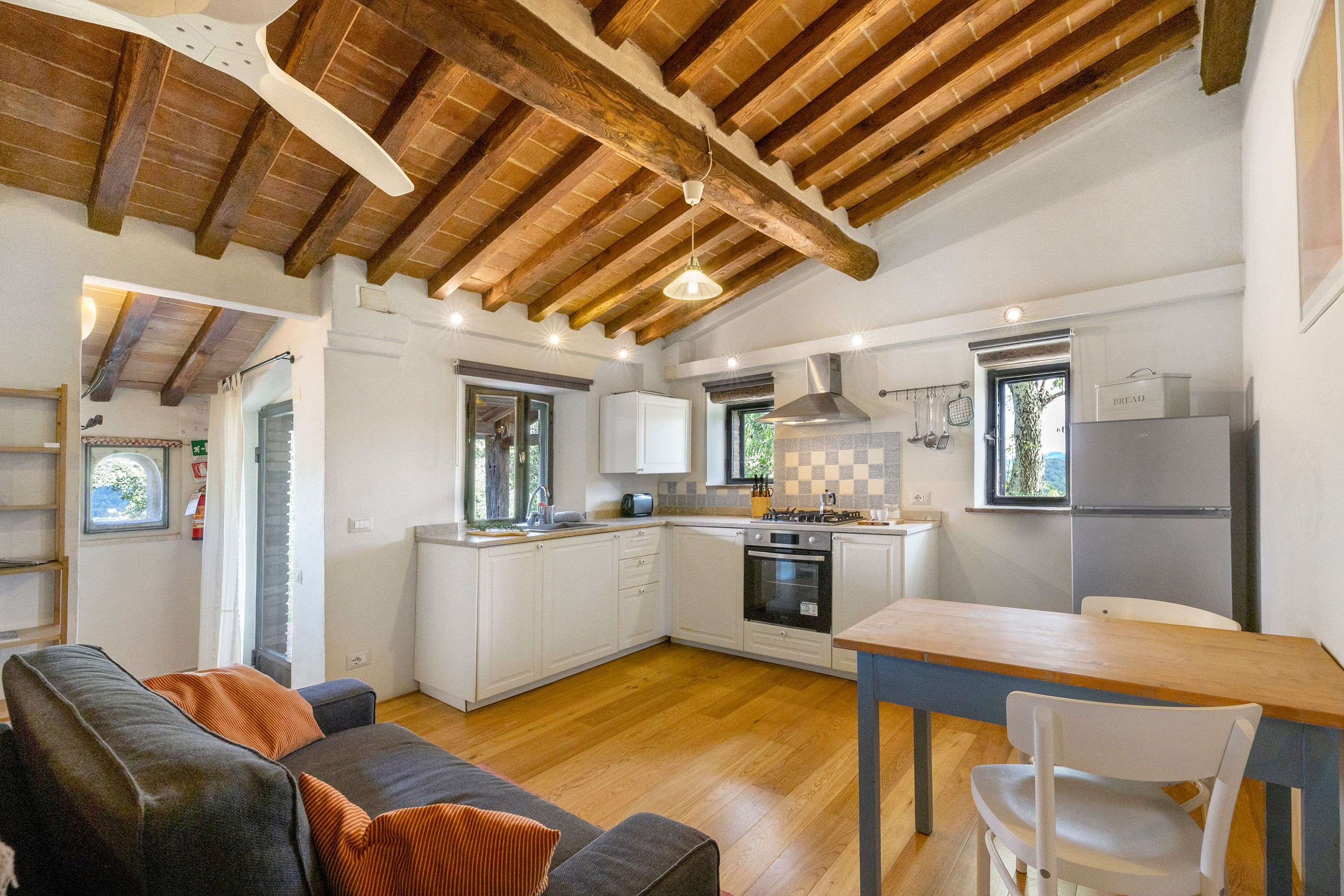 A compact kitchen with white cabinets, a built-in oven, and a dining area with a table and chairs.