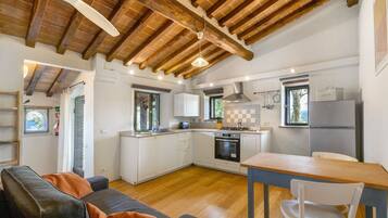 A compact kitchen with white cabinets, a built-in oven, and a dining area with a table and chairs.