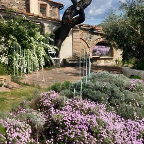 A garden with a stone bridge, flowering plants, and a white chair.