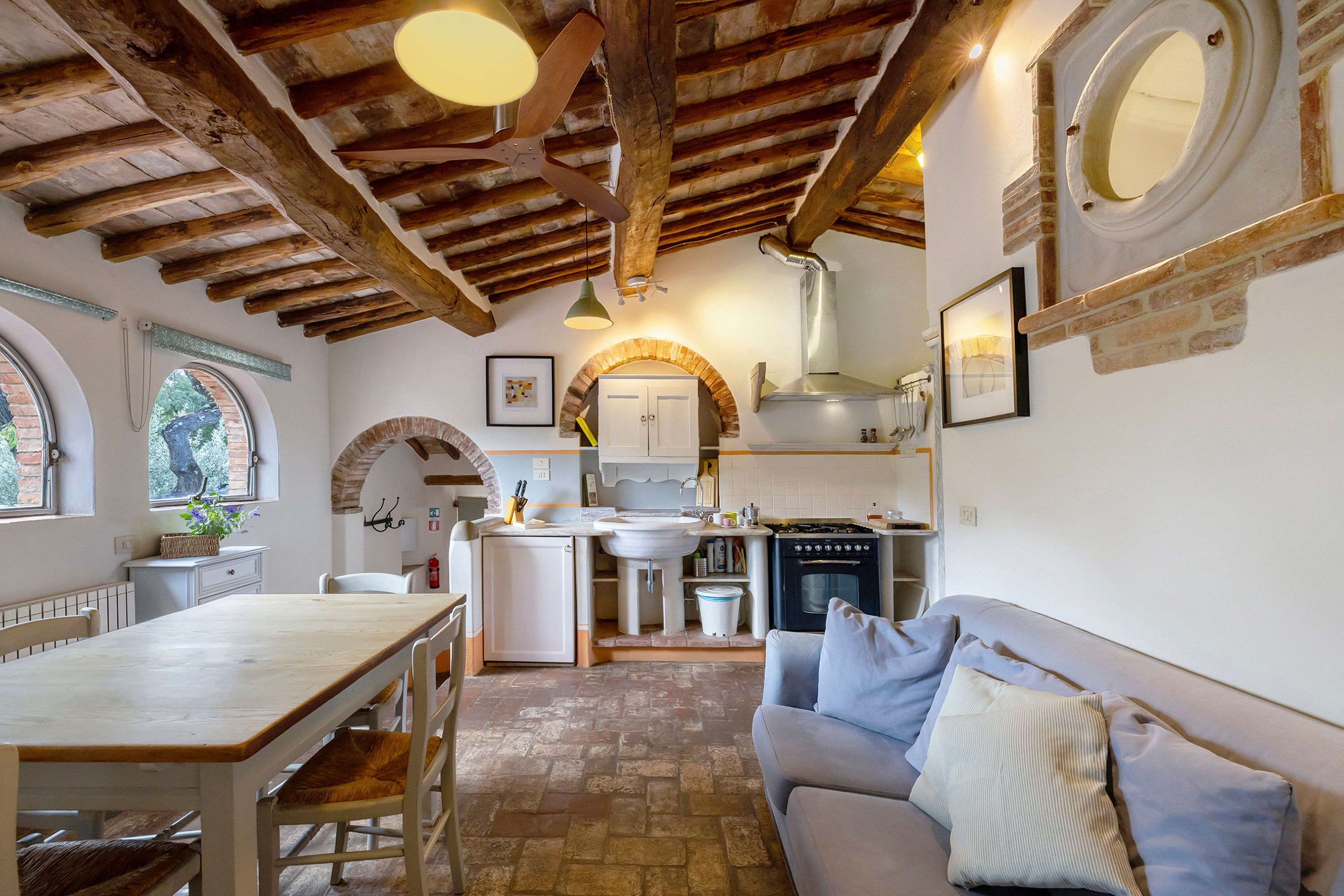A cozy kitchen with a dining area, a built-in oven, and a stone floor.