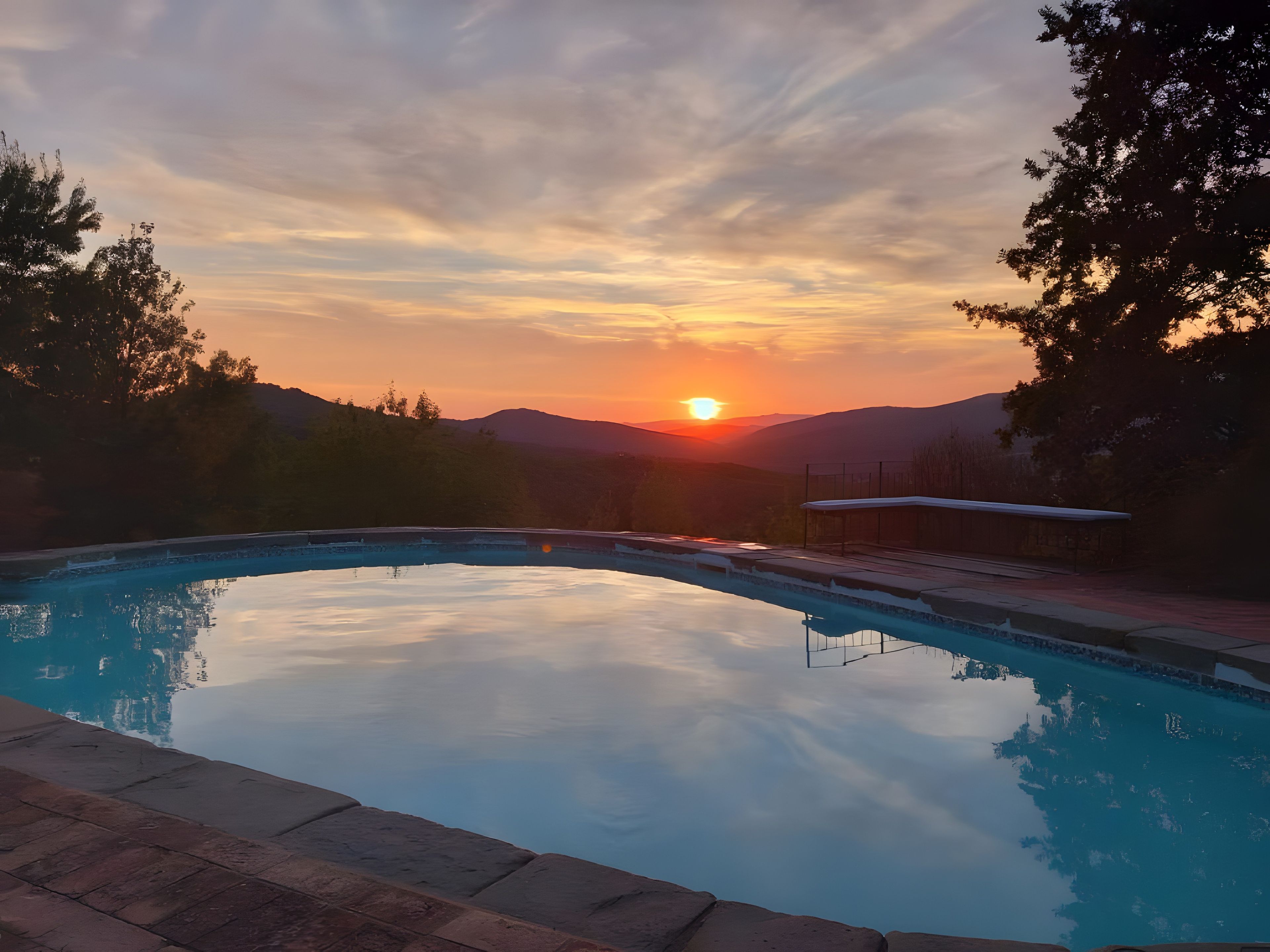 Una piscina con vista despejada al atardecer y montañas al fondo.