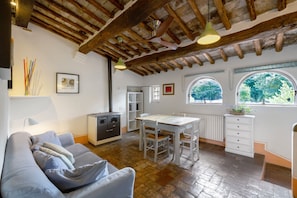 A cozy kitchen with a dining table, a built-in oven, and a window with a view of trees.