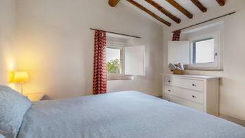 A bedroom with a bed, a dresser, a window with a view, and a lamp.