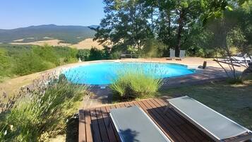 Une piscine avec une terrasse en bois et des chaises longues.