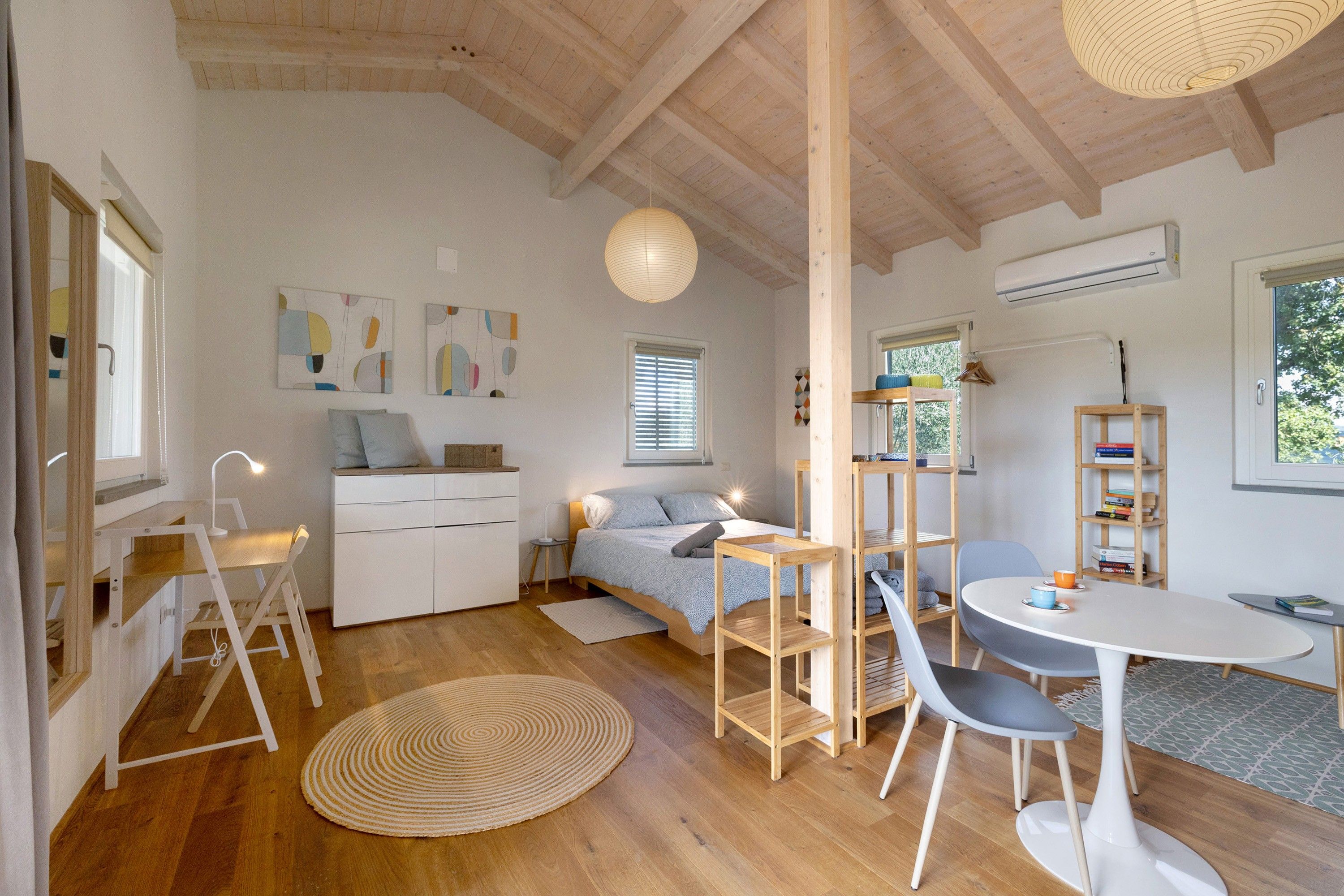 Een kamer met een bed, een bureau, een stoel, een rond tapijt en een boekenkast.