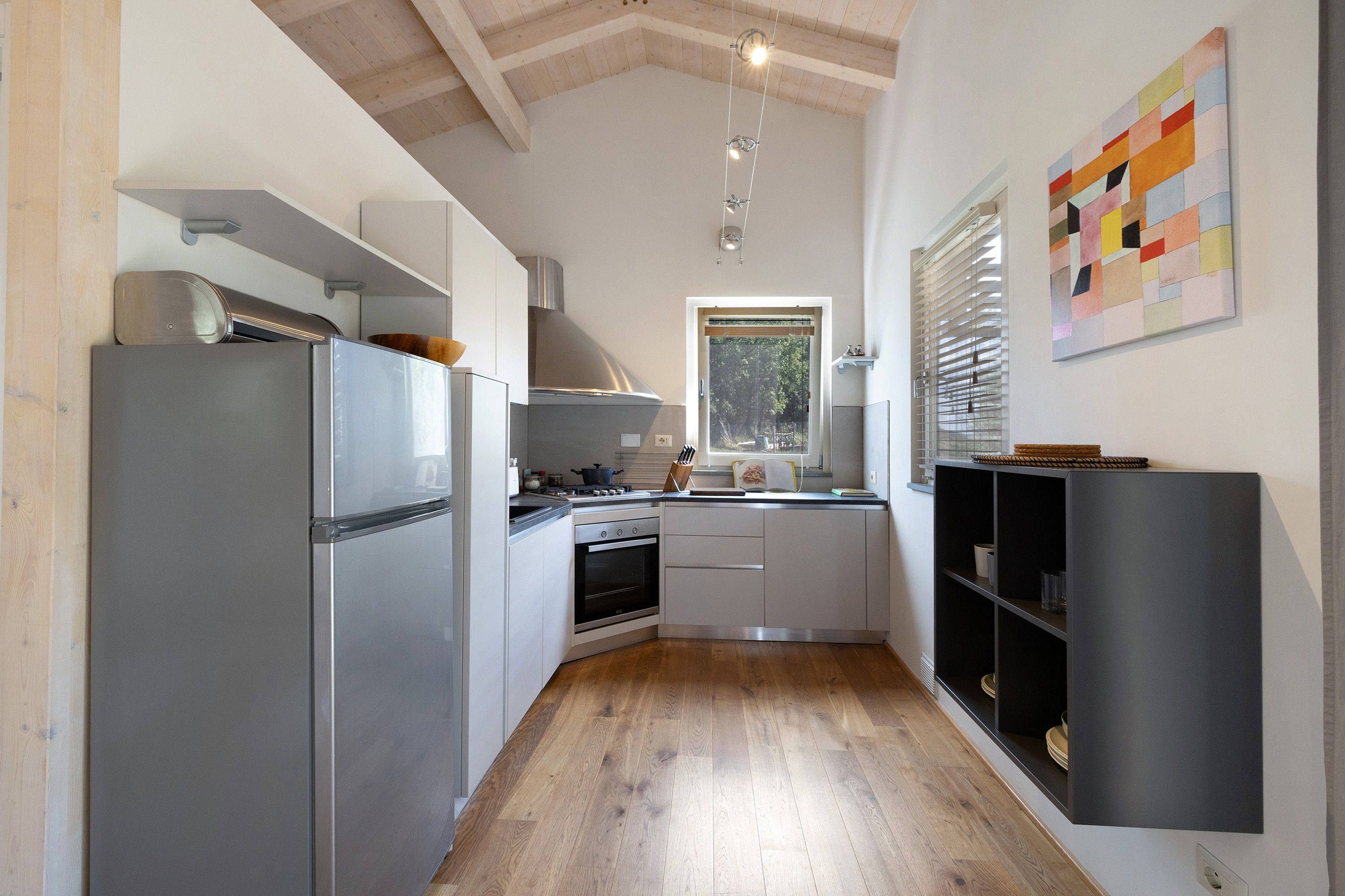 Una cocina moderna con refrigerador de acero inoxidable, horno empotrado y una ventana que proporciona luz natural.