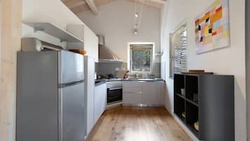 Una cocina moderna con refrigerador de acero inoxidable, horno empotrado y una ventana que proporciona luz natural.