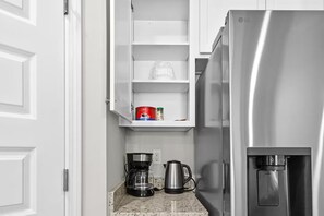 Eine Küche mit einem Edelstahl-Kühlschrank, einer Kaffeemaschine und einem Wasserkocher auf der Arbeitsfläche.