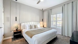 A bedroom with a large bed, bedside tables, a ceiling fan, and a window with curtains. - 4-bedroom house with private pool in Storey Lake (Kissimmee)