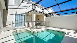 Ein Pool mit Glasumrandung, einer überdachten Lounge und Blick auf einen klaren Himmel.