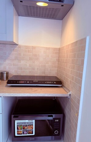 Una cocina con una balanza digital Zephyr sobre la encimera y un horno microondas de convección Koenic debajo.