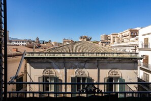 Un bâtiment doté d’un toit recouvert de tuiles, de nombreuses fenêtres avec volets et d’un balcon agrémenté de balustrades.