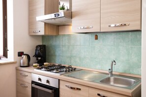 Une cuisine moderne équipée d’une cuisinière à gaz, d’une machine à café et d’un évier en acier inoxydable.