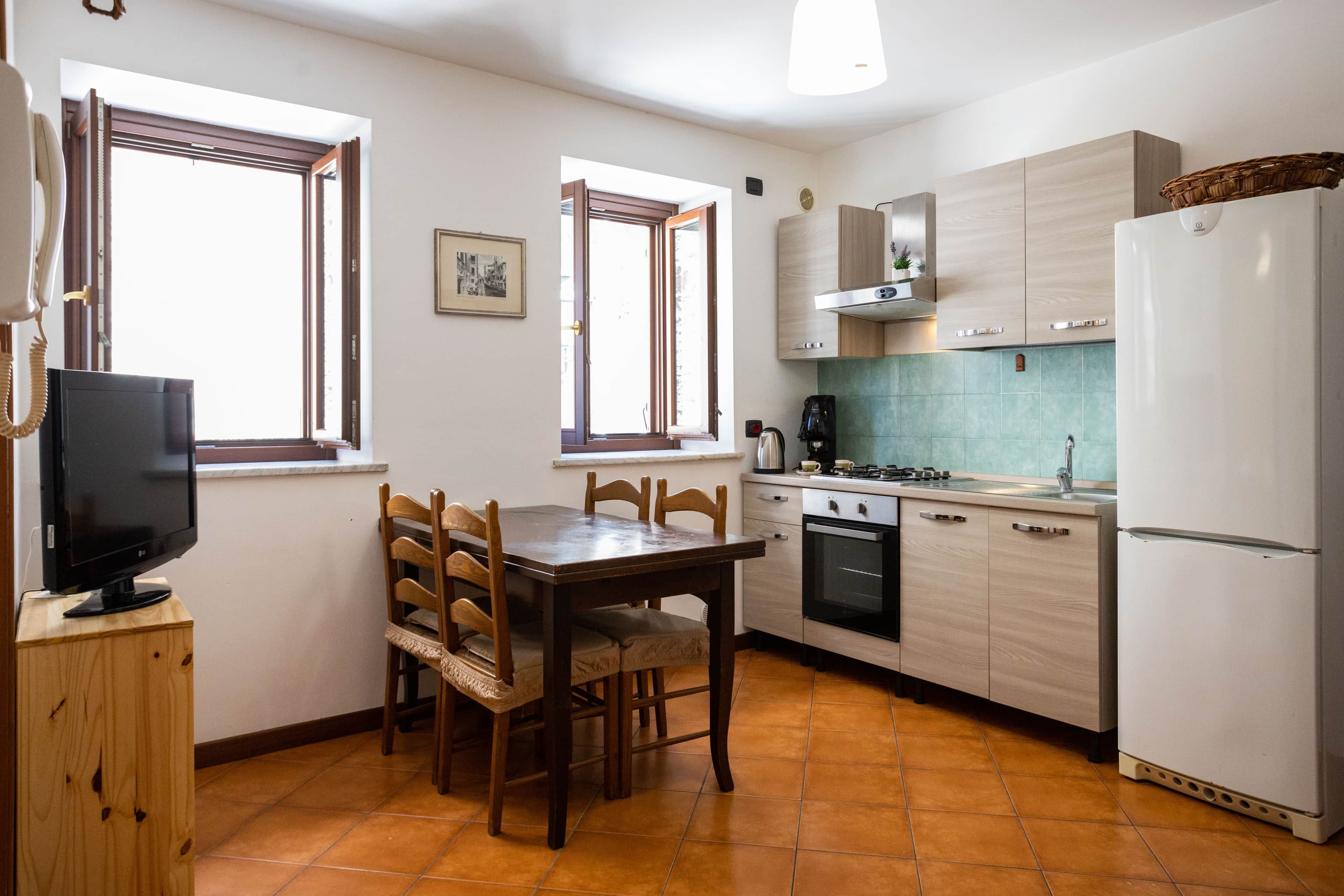A compact kitchen with a dining table, chairs, a refrigerator, and a stove.