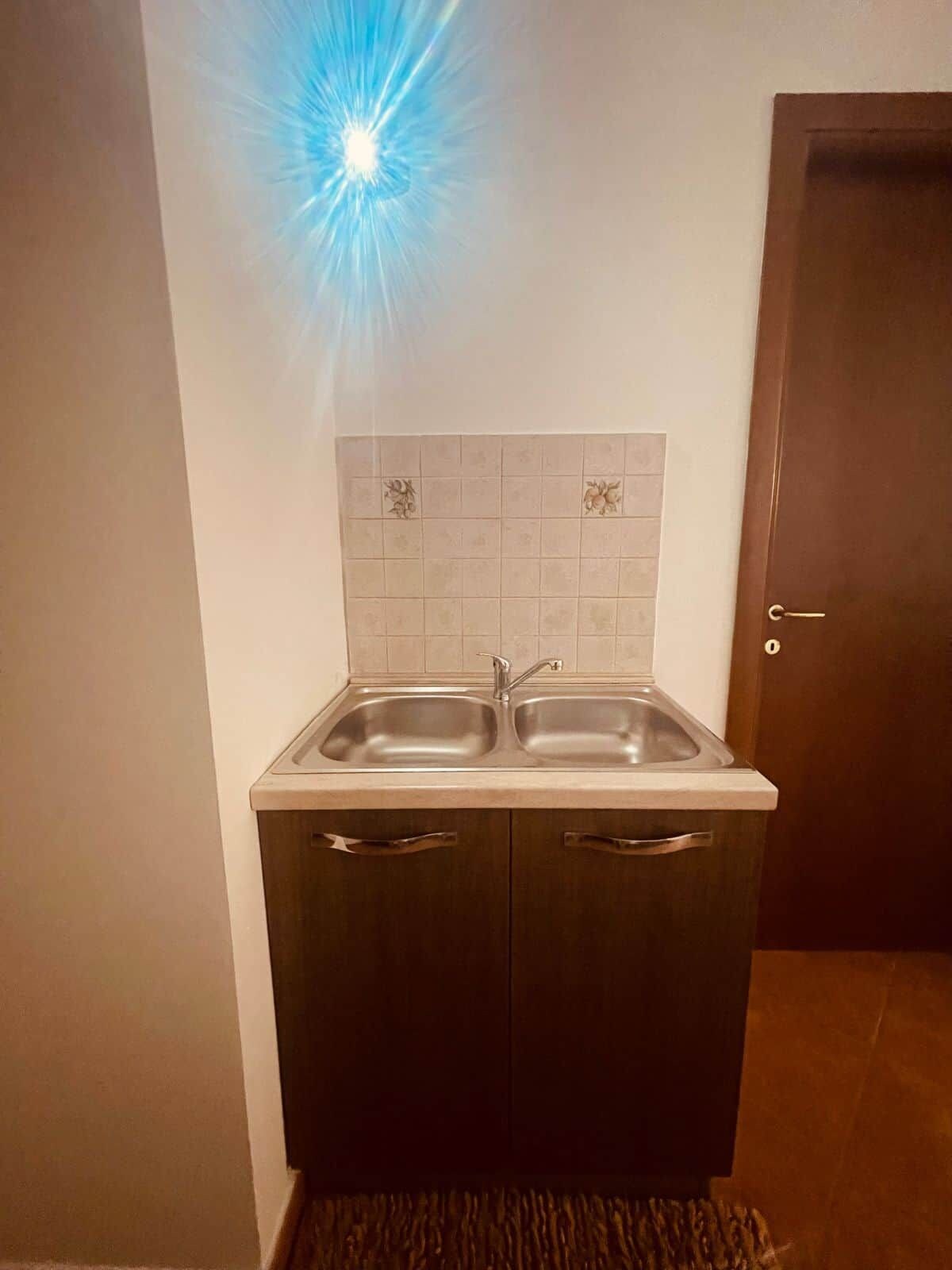 Eine Küche mit zwei Spülen, einem Schrank mit Griffen und einer gefliesten Rückwand.